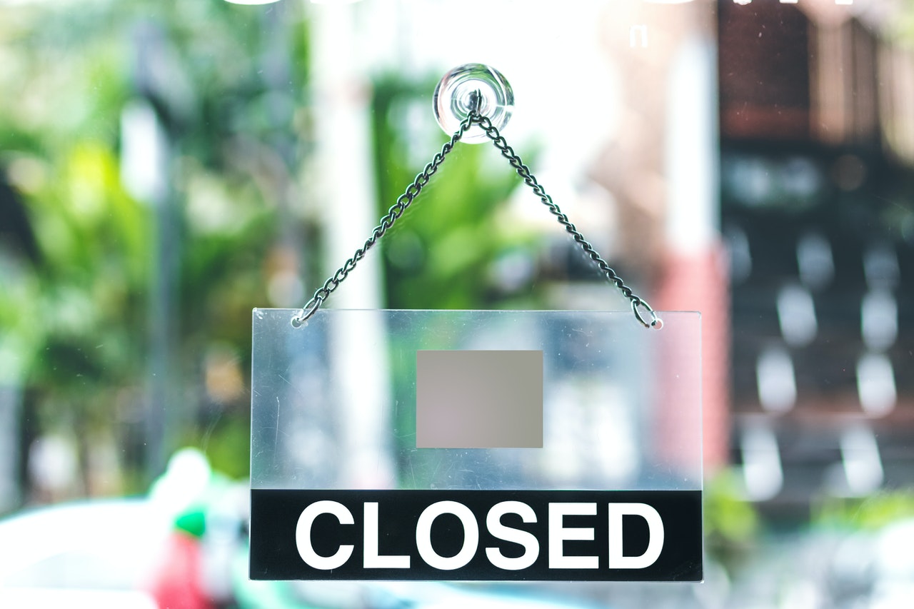 plexiglass-closed-sign-on-door-of-business