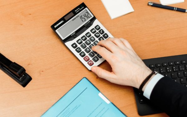 person-using-calculator-on-brown-desk