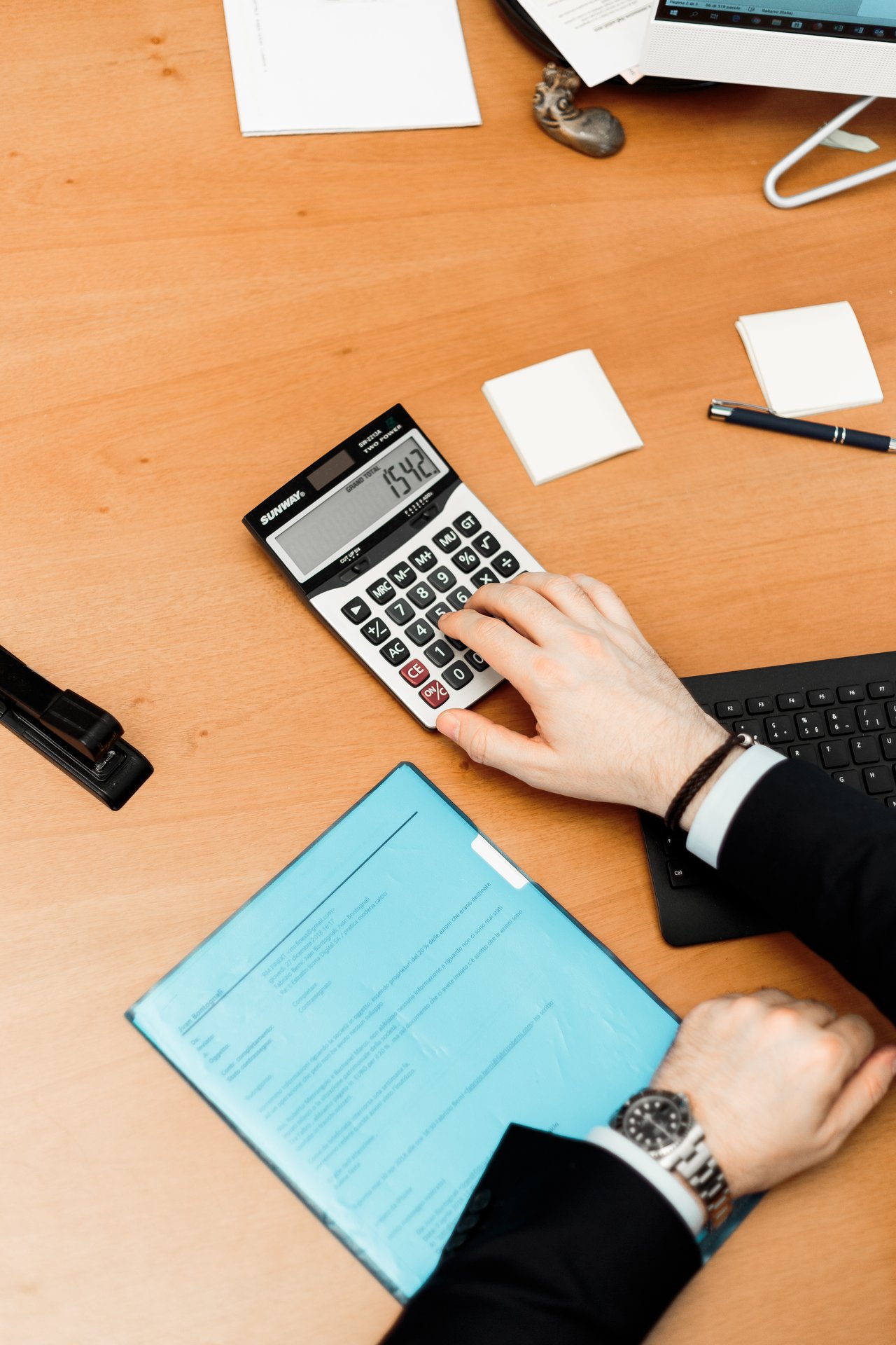 person-using-calculator-on-brown-desk