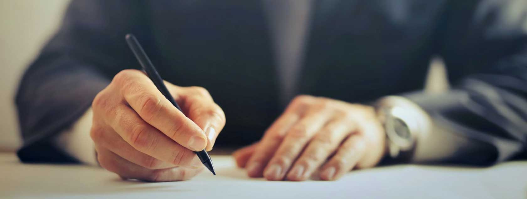 hands-of-a-man-writing-with-pen-sitting-at-desk