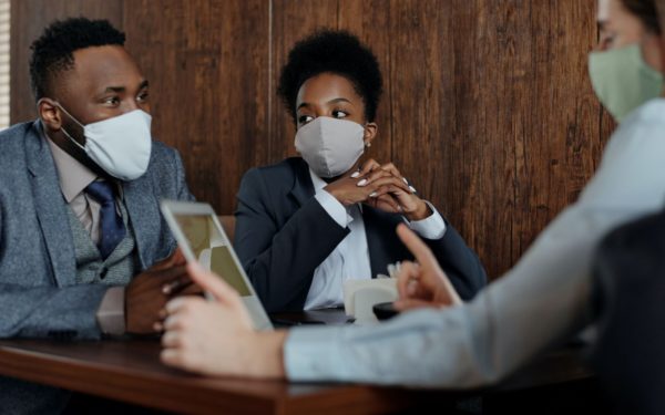 three-business-people-sitting-at-table-wearing-masks