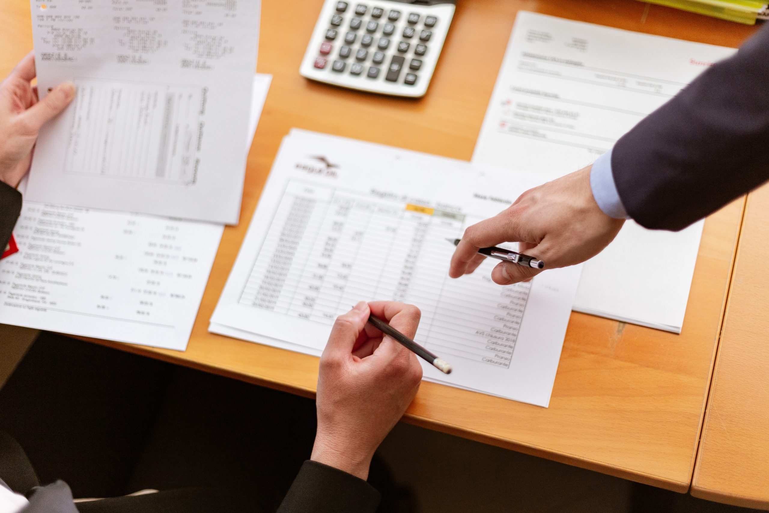 desk-with-papers-and-two-mens-hands-pointing