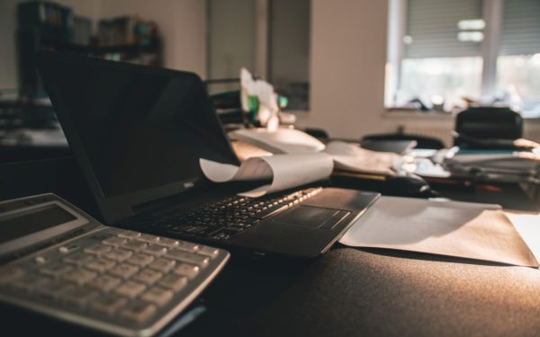 laptop-on-desk-with-papers-in-dimly-lit-office