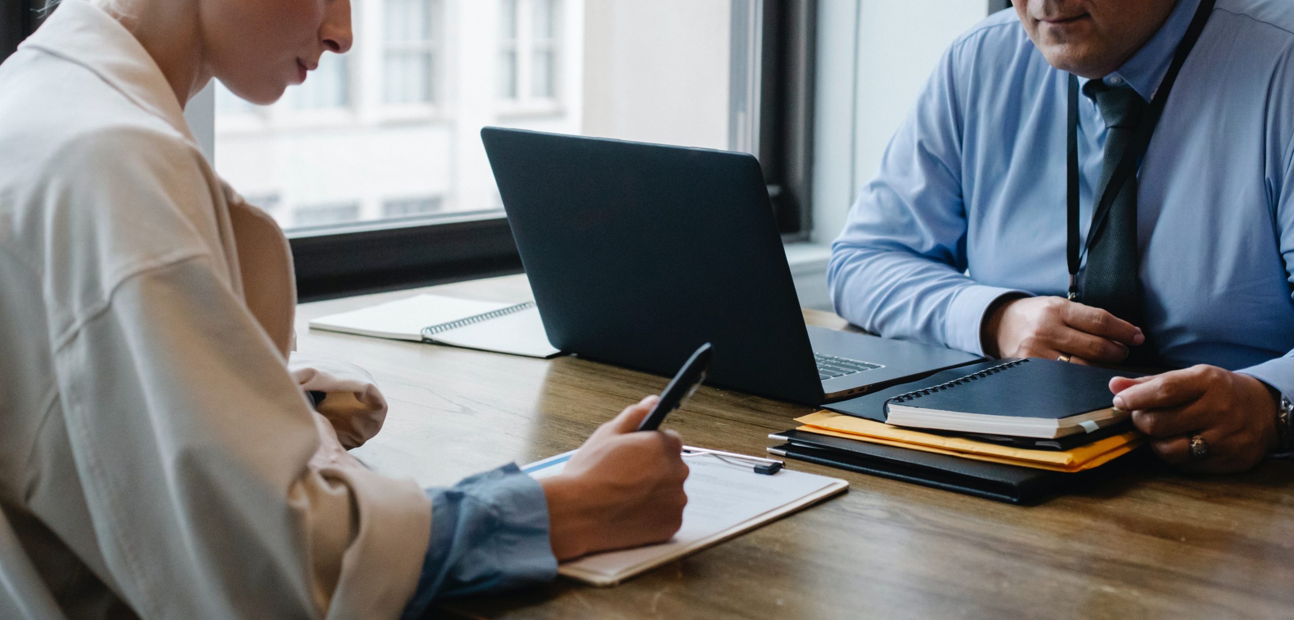 woman-writing-notes-at-desk-during-meeting