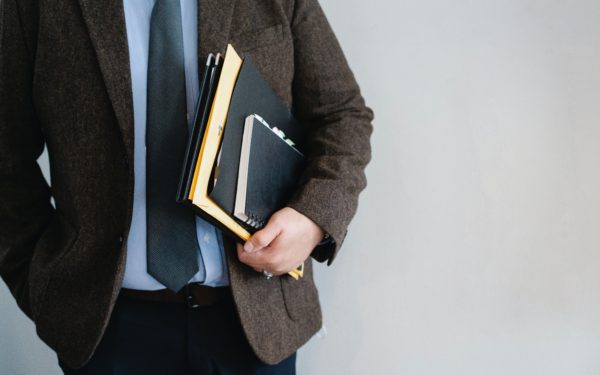 man-holding-notebook-and-paperwork-under-his-arm