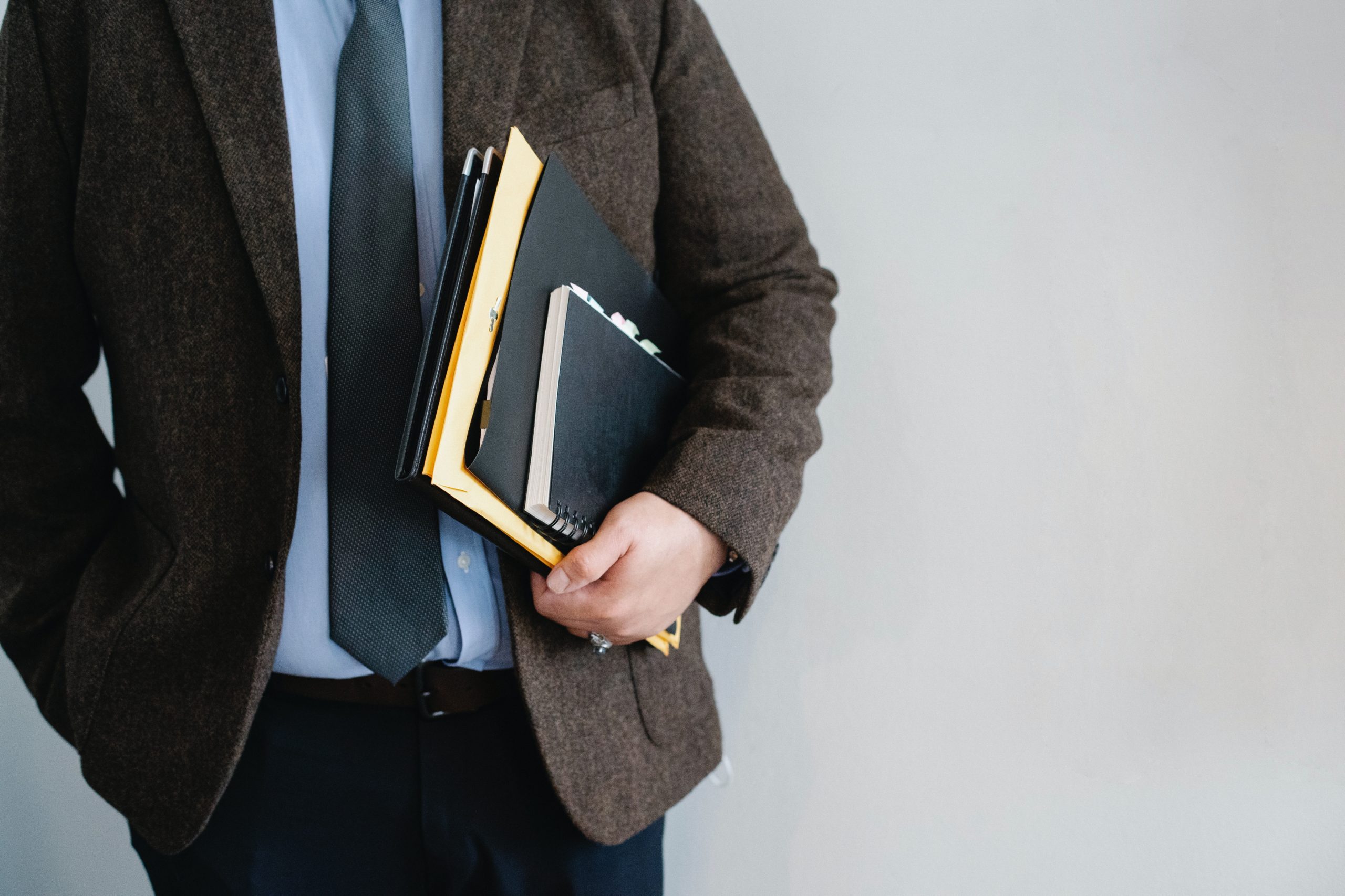 man-holding-notebook-and-paperwork-under-his-arm
