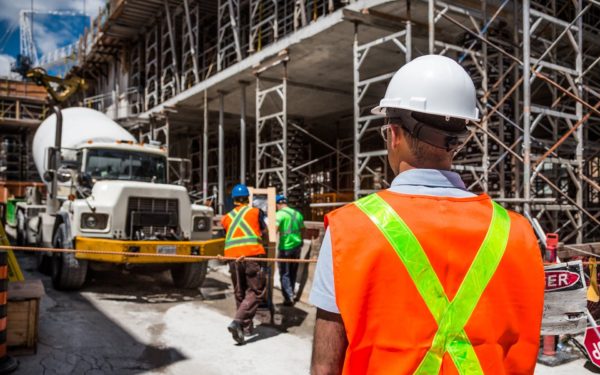 Man-in-hard-hat-with-back-turned-faces-construction-site