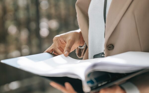 woman-in-beige-coat-holding-binder-of-papers