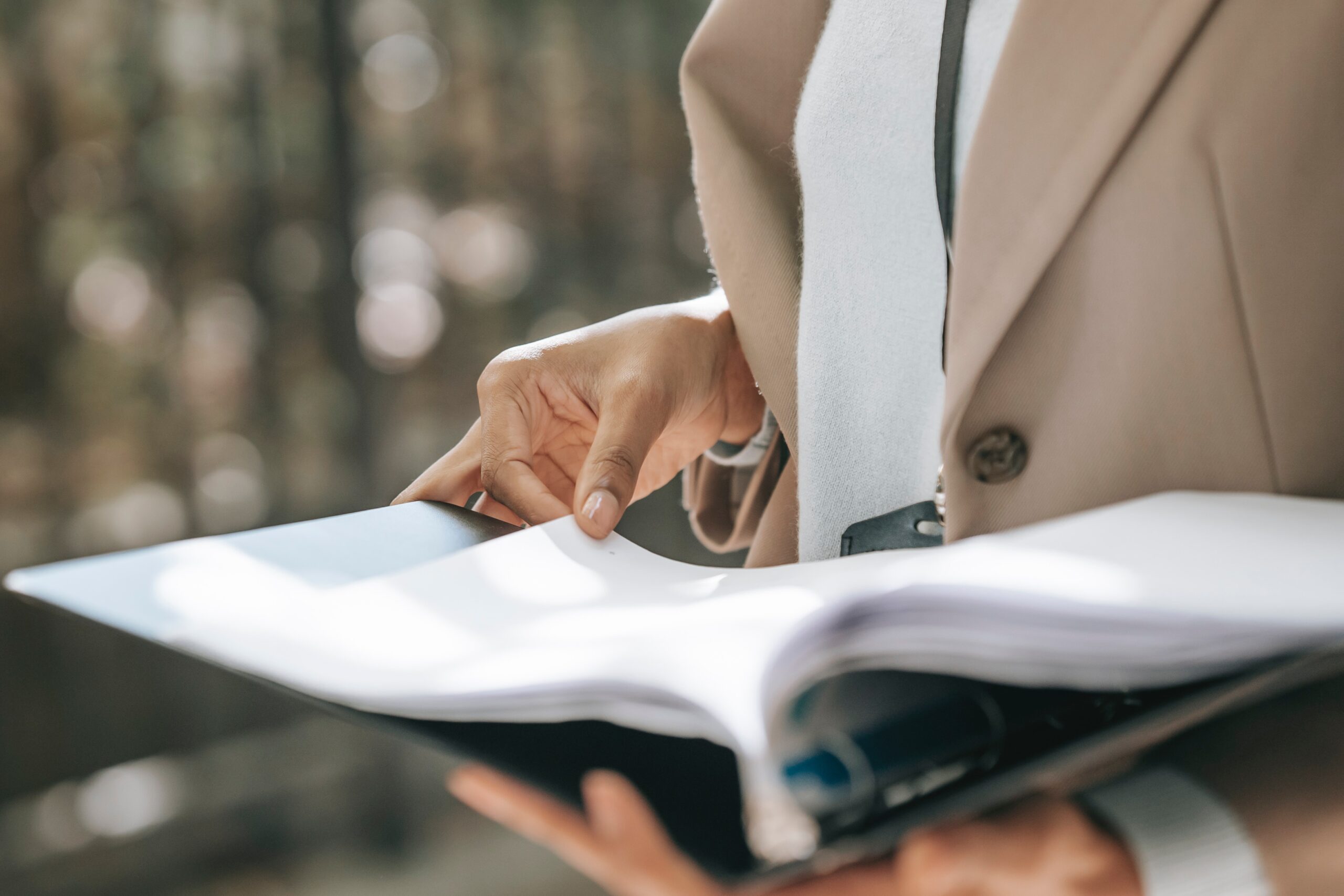 woman-in-beige-coat-holding-binder-of-papers