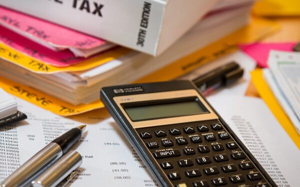 calculator-sitting-on-top-of-paperwork-next-to-income-tax-book