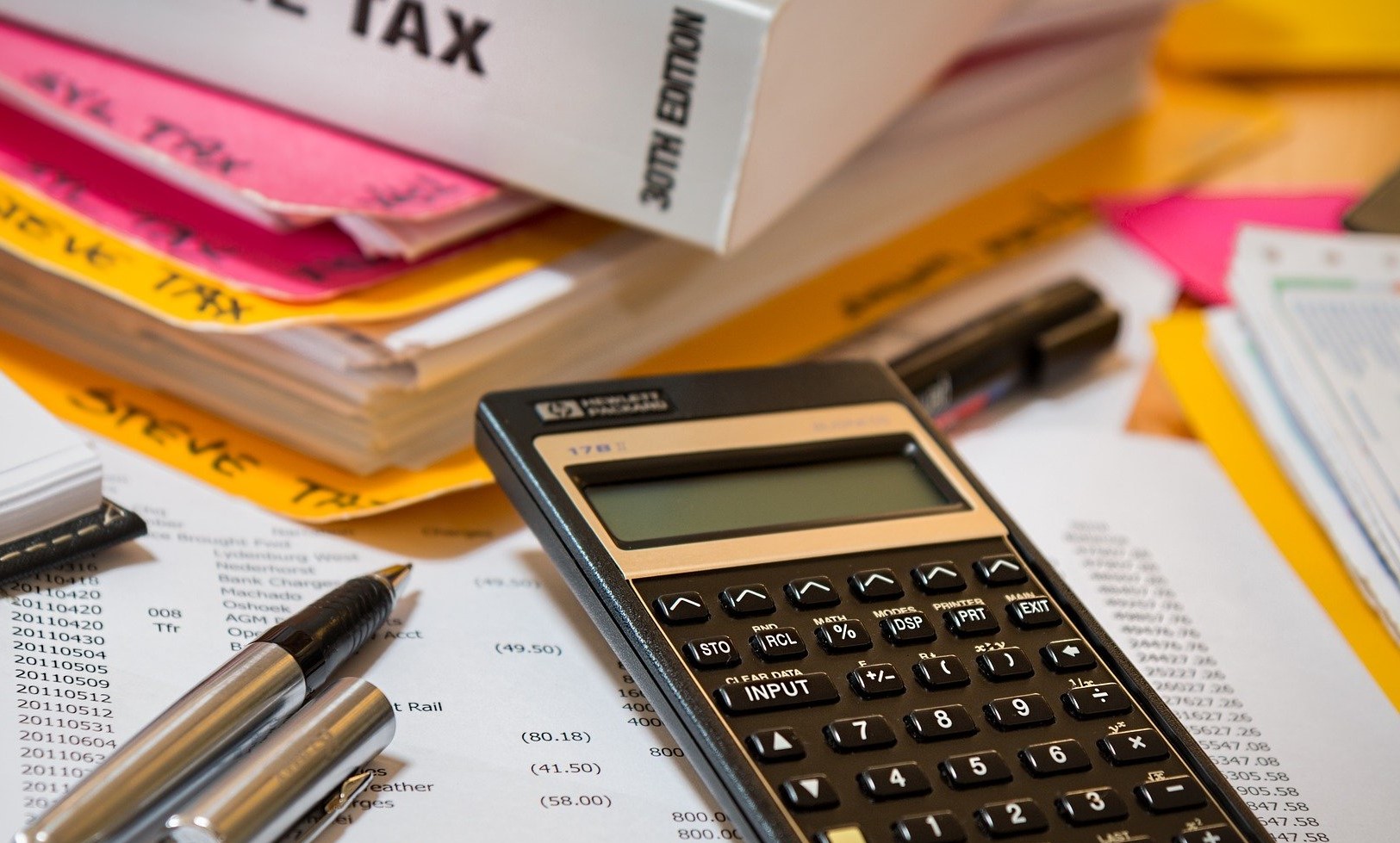 calculator-sitting-on-top-of-paperwork-next-to-income-tax-book