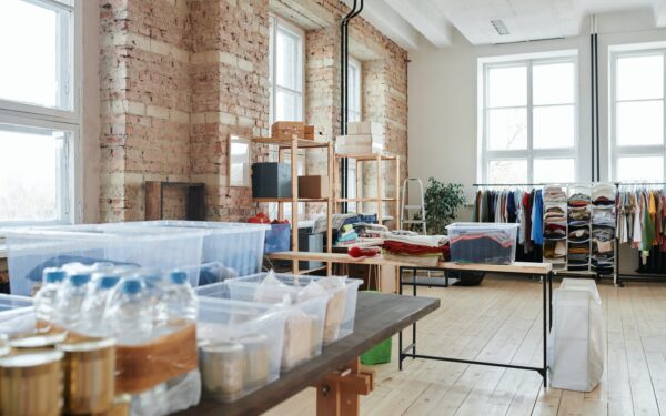large room full of clothing donations hanging on racks and sorted into plastic bins