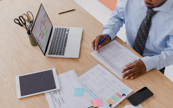 man working at desk with papers laptop and ipad