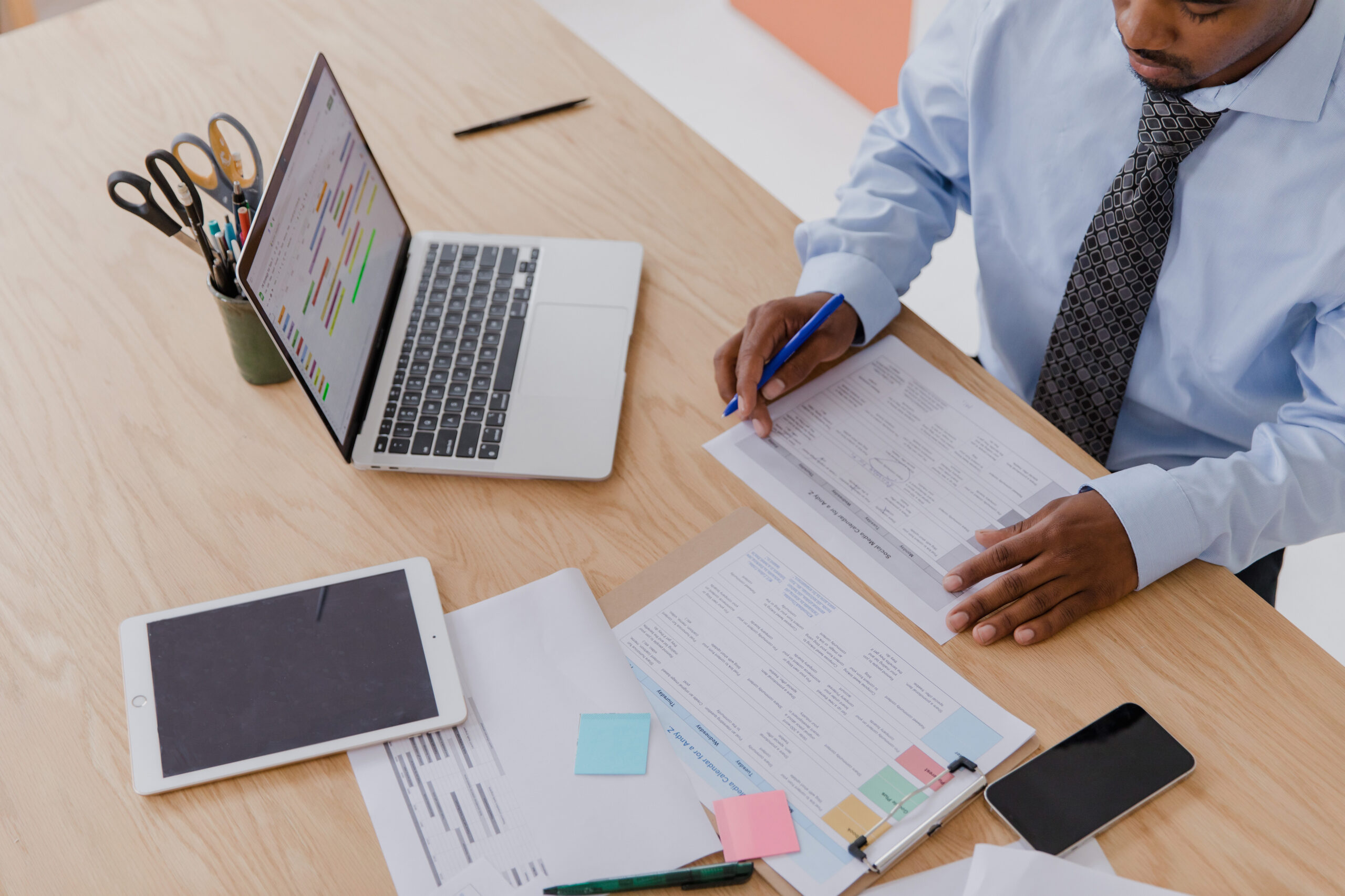 man working at desk with papers laptop and ipad