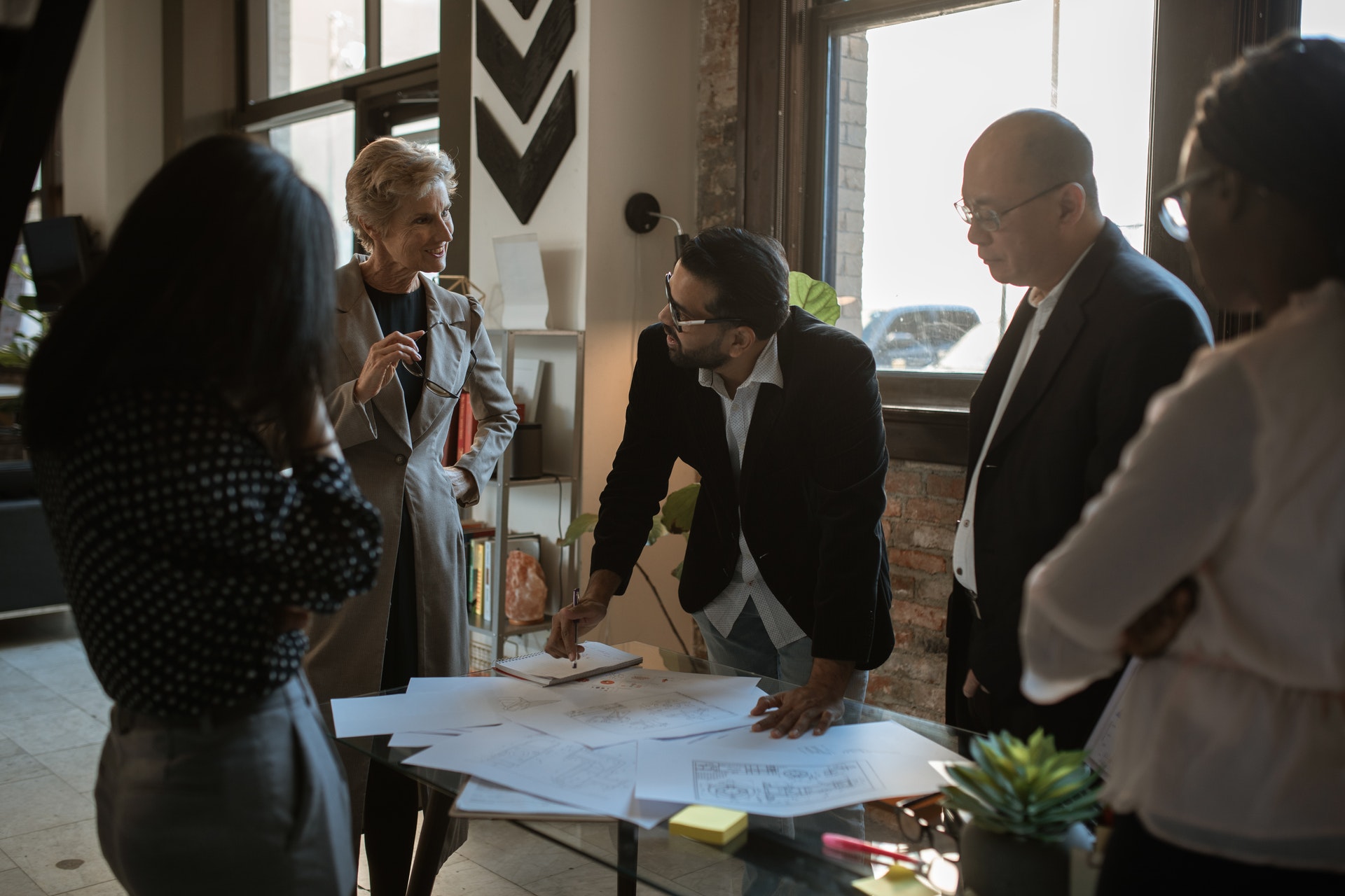 Group of people standing around desk looking at blueprint of office