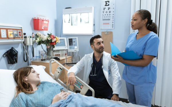Woman lying in hospital bed talking with two doctors