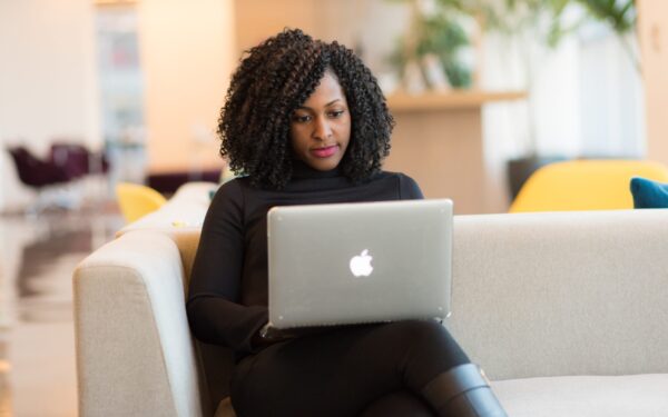 woman sitting on coach holding macbook
