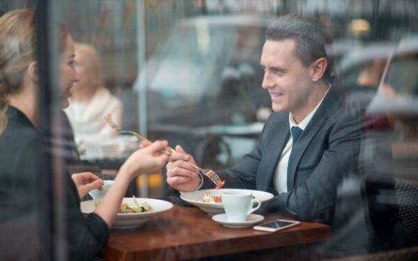 woman sitting across from man in business attire eating a meal and talking