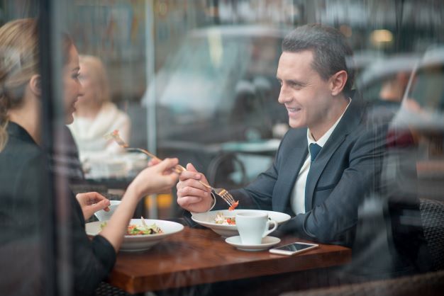 woman sitting across from man in business attire eating a meal and talking