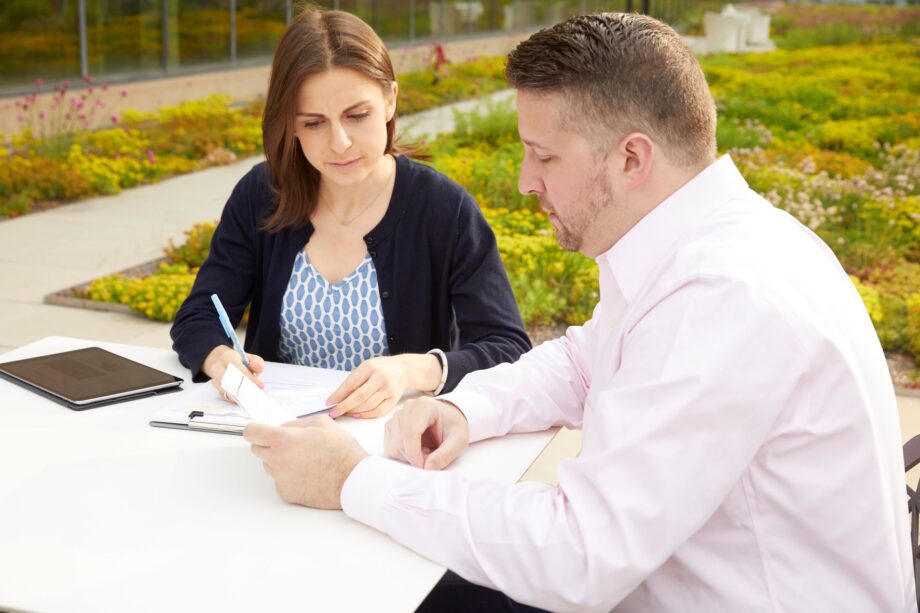 Woman and man sit on patio looking at documents on table